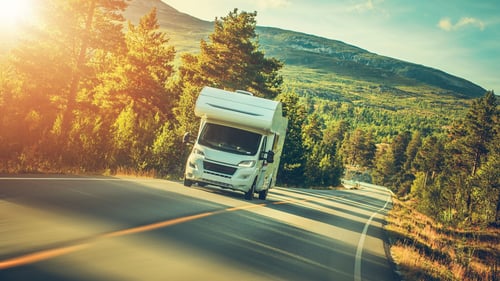 A camper van set against a beautiful natural backdrop, ready for a summer road trip adventure.