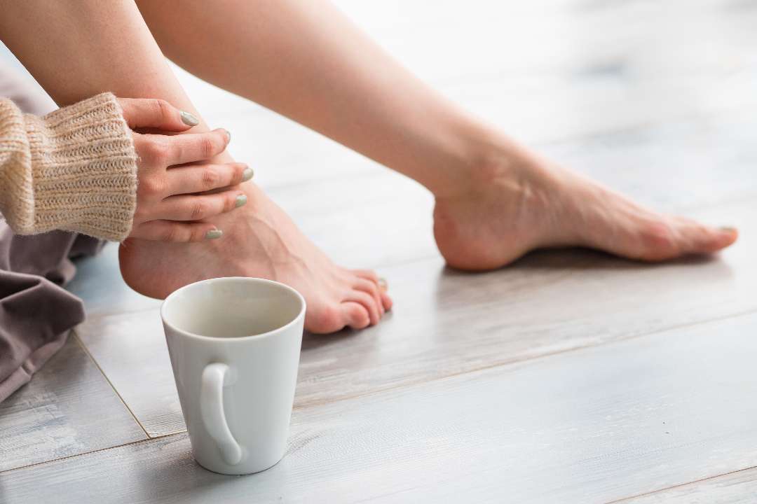 Person with morning foot and ankle pain while holding their ankle