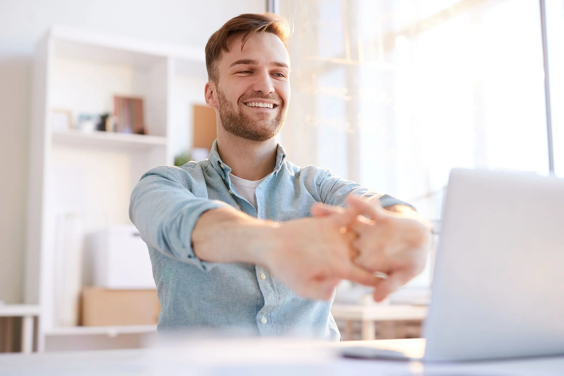 man sitting at desk doing stretches
