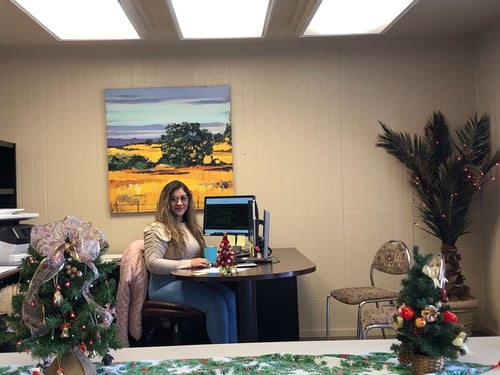 Team member sitting at brown desk in office decorated in holday decor