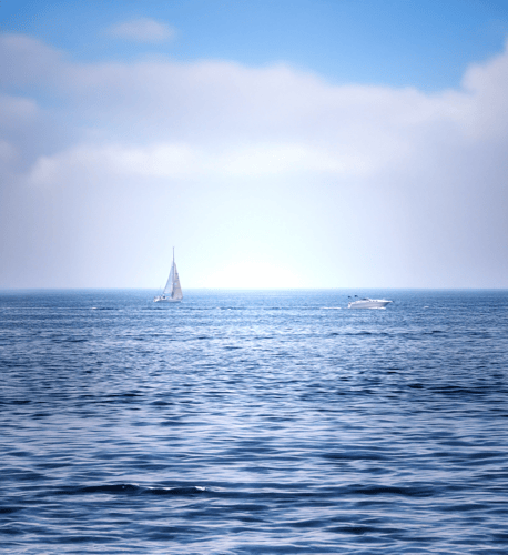 A serene image of a sail boat and a speed boat floating on a bed of water.