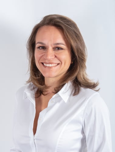 Eine Frau in weisser Bluse lächelt in die Kamera.