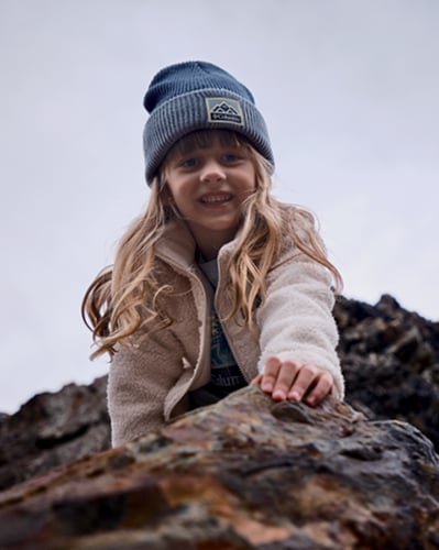 Smiling girl rock climbing in blue hat