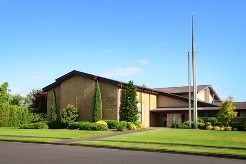 Brick church building surrounded by beautiful green landscape.