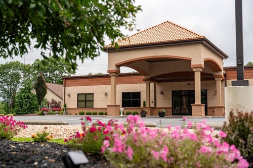 Capture the welcoming exterior of Tom Trella, featuring a clean and professional commercial building with a landscaped entrance. This image highlights the business location, making it easy for customers to recognize and visit while showcasing a well-maintained and inviting storefront.