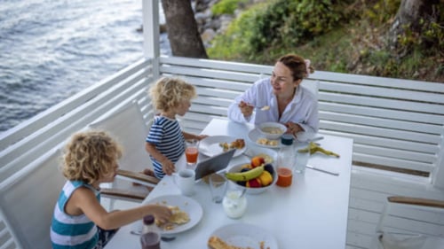Family sitting by water eating a meal