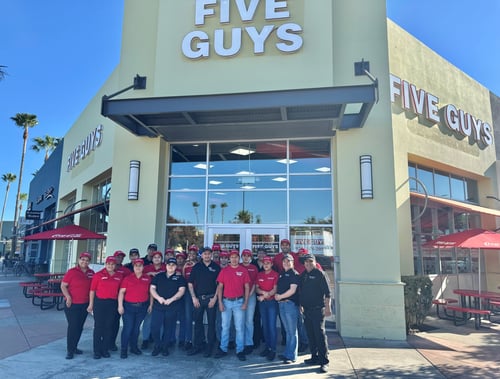 Employees pose for a photograph outside the entrance to the Five Guys restaurant at 4930 Dublin Boulevard in Dublin, California.