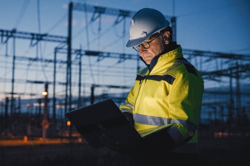 An engineer using a laptop at a dark power plant.