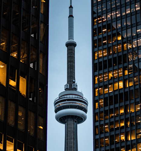 Close up view of the CN Tower between two high rise office buildings.