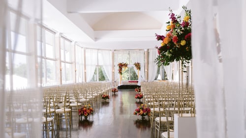 Large wedding ceremony area with a floral altar and gold and white chairs