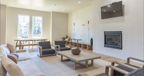 A living room with a grey couch, a wooden coffee table, and a television mounted on the wall.