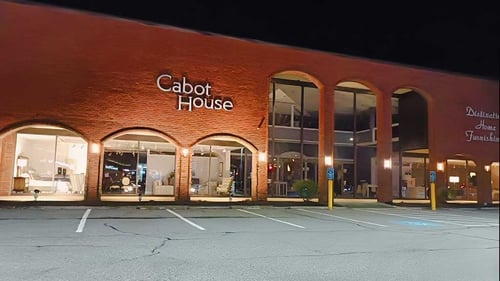 Storefront of the Burlington location of Cabot House Furniture at night.