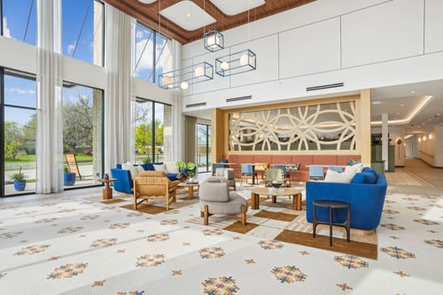 Bright lobby with modern furniture, large windows, and patterned tile floor.