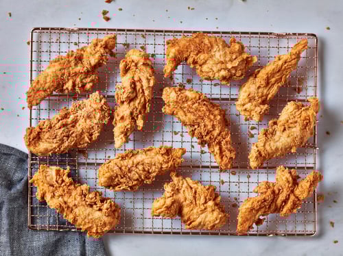 Assorted pieces of golden fried chicken on a cooling rack
