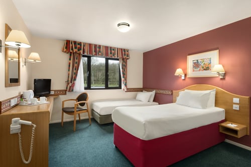 Bedroom with two single twin beds, TV, desk and tea and coffee making facilities