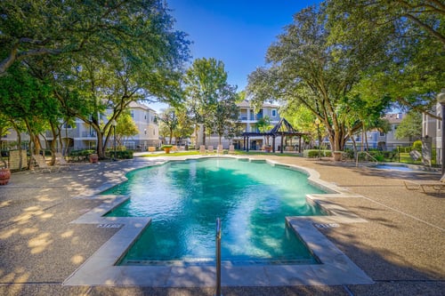 Resort style pool shaded by trees at Saxony at Chase Oaks, Plano, Texas