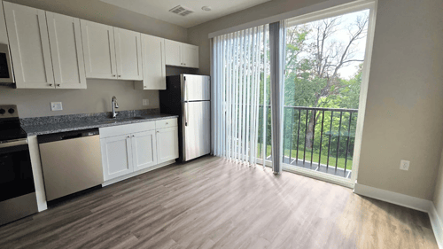 Kitchen and living area with balcony of an available apartment unit at Greenwood Commons Apartments in Delaware, OH.