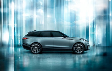 Side view of a silver Range Rover Sport in a modern glass interior setting.