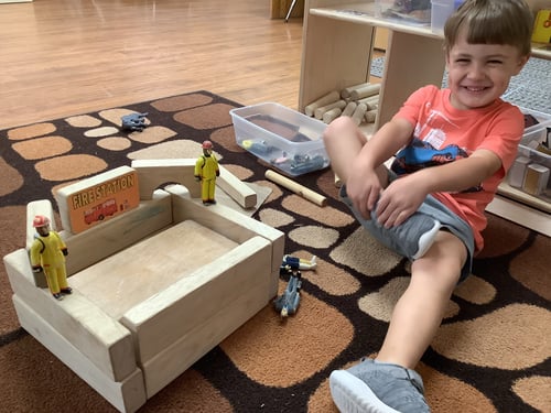 Child stacking colorful blocks to build an imaginative fort.