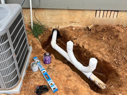 A pipe break repair next to an AC condenser. The pipe break has been excavated and replaced