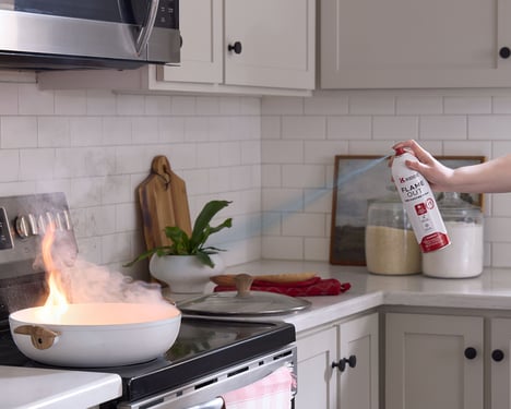 A person uses the Flameout Spray on a fire in a frying pan.