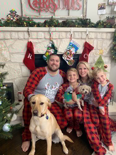 Agent Ryan sitting and smiling with family and dog in Christmas pajamas