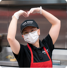 A collection of red uniformed restaurant crew members working and smiling.