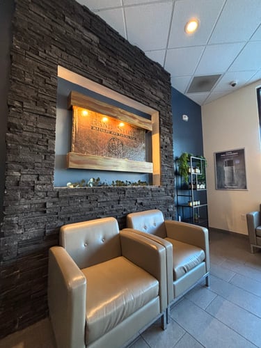 Waiting area with stone waterfall feature and comfortable seating at Hand & Stone Massage and Facial Spa Dayton OH