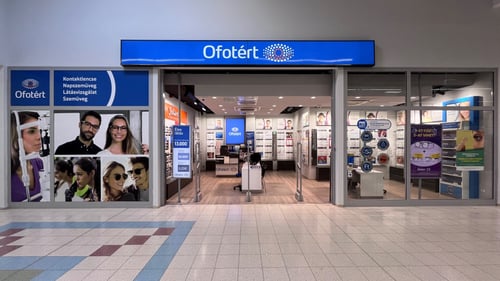 Ofotért üzlet bejárata Mátészalkán, a Tesco áruházban, üvegportálos homlokzattal és kivilágított belső térrel.