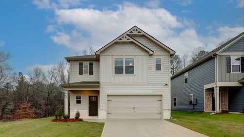 Tan 2 story home with siding and brick front and two car garage in the DRB Homes Village at Waterford community