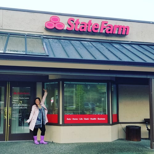 Juanita standing and smiling in front of tan building with red State Farm sign
