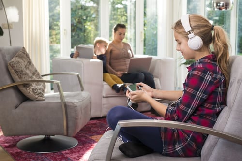 Girl with headphones sitting in chair near woman and boy
