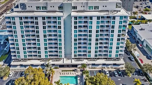 An aerial view of a large building with a pool and parking lot at Elements on Third Apartments, St. Petersburg, FL