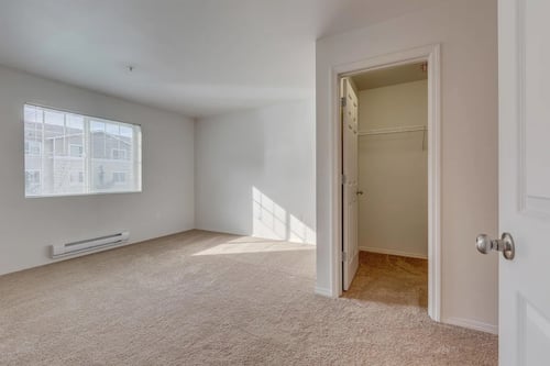 A room with a carpeted floor and a door leading to another room at Valley Springs Apartments, Renton