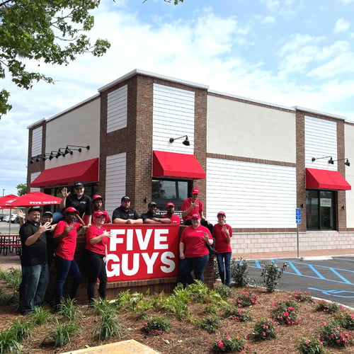 Employees pose for a photograph around the exterior sign in front of the new Five Guys restaurant at 241 South Greeno Road in Fairhope Alabama.