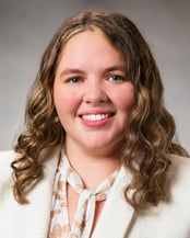Ashley smiling in front of a gray background.