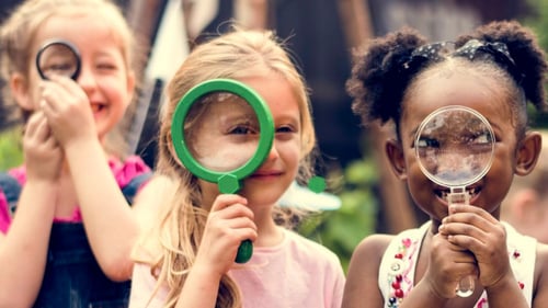 3 kids holding up magnifying glasses to their faces