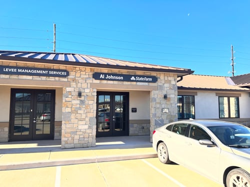 Tan stone building with black and white State Farm sign out front
