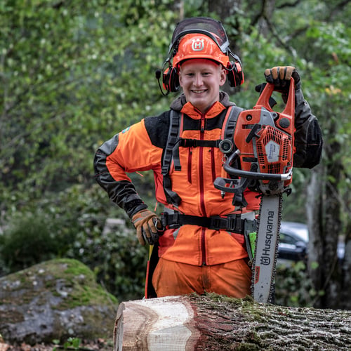 Mann im Wald mit Husqvarna Motorsäge und Husqvarna Bekleidung