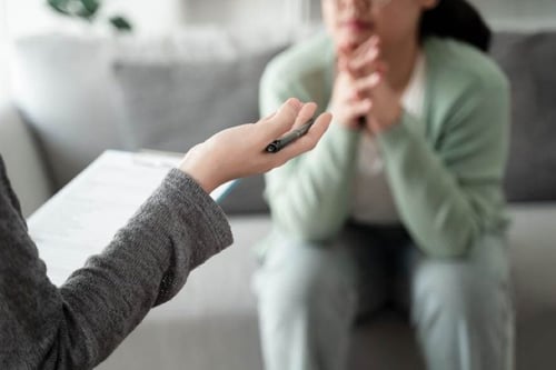 Therapist in Oakdale MN holding clipboard and speaking with a patient during an individual counseling session at Sonder Behavioral Health.