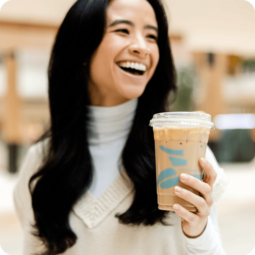 Woman smiling and drinking a latte