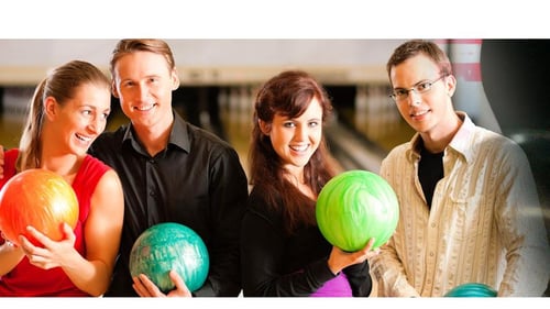 four people holding colorful bowling balls