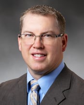 Nathan Gilbertson, PA-C smiling in front of a gray background.