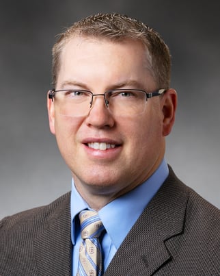 Nathan Gilbertson, PA-C smiling in front of a gray background.