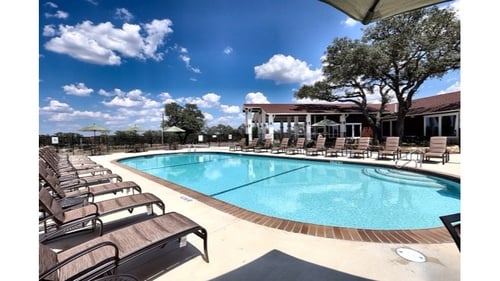 A large outdoor swimming pool surrounded by sun loungers at Vineyard Springs Apartments in Johnson City, TX, 78636