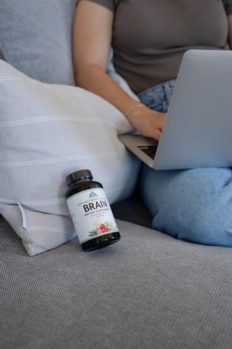 supplement bottle on couch with person holding laptop