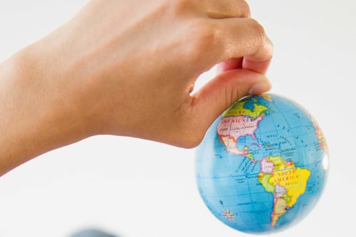 Hand holding globe representing charitable expeditions and global community impact.
