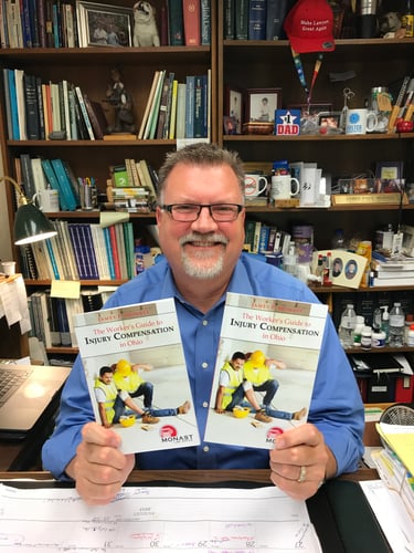 James Monast holding his new book for injured workers