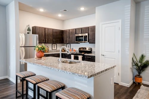 Modern kitchen with granite countertops, stainless steel appliances, and dark wood cabinets.