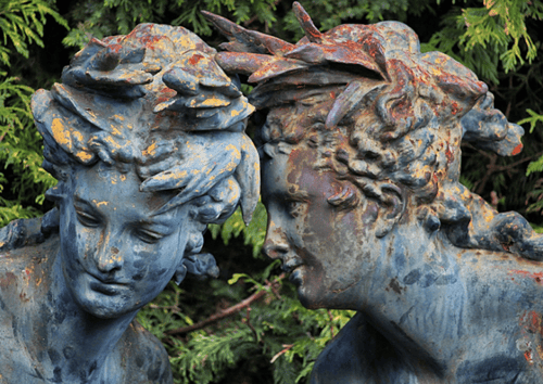 A statue of two figures whispering to another.